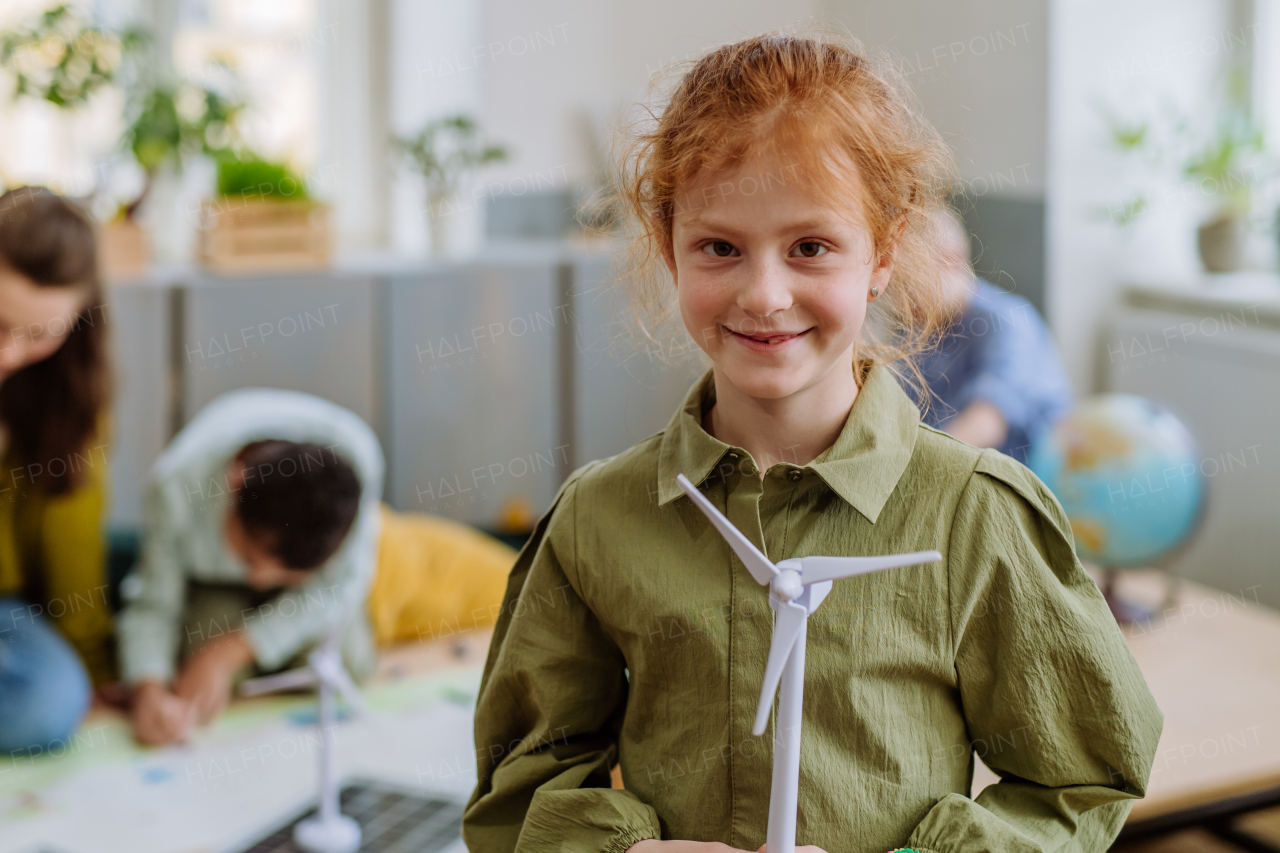 Little girl posing with a model of winter turbine during school lesson.