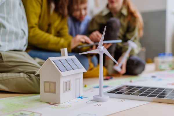 Close-up of a house model with solar system and wind turbine during a school lesson.