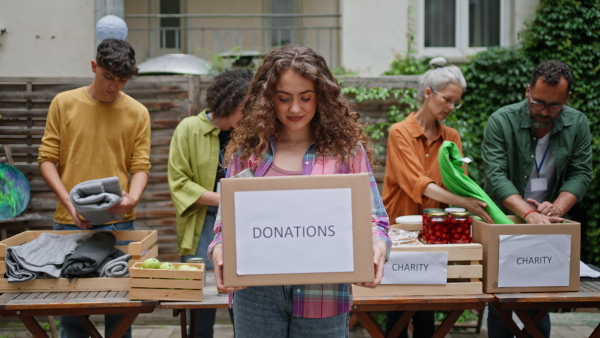 A collection drive. Volunteers collecting food resources and clothes to support people in need, working together.