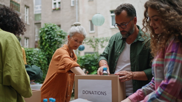 A collection drive. Volunteers collecting food resources and clothes to support people in need, working together.