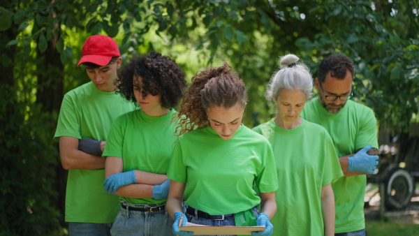 Group of volunteers picking trash, removing litter from forest, protecting nature and wildlife. Forest cleanup. Environmental education program by local community.