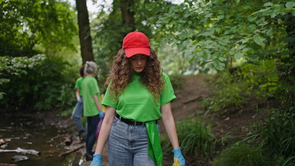 A video of female volunteer working in forest, cleaning after natural disaster, holding bags full of trash. Forest cleanup. Environmental education program.