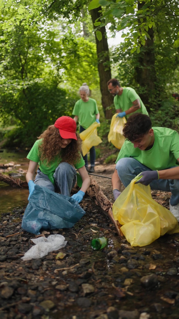 Group of volunteers picking trash, removing litter from forest, protecting nature and wildlife. Forest cleanup. Environmental education program by local community.