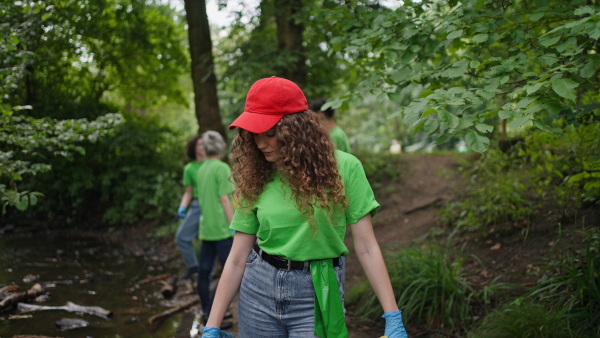 A video of female volunteer working in forest, cleaning after natural disaster, holding bags full of trash. Forest cleanup. Environmental education program.