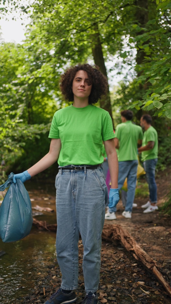 A video of female volunteer working in forest, cleaning after natural disaster, holding bags full of trash. Forest cleanup. Environmental education program.