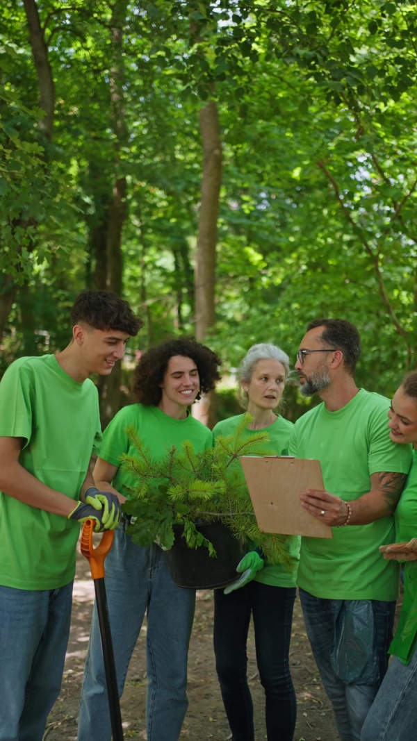 Group of volunteers picking trash, removing litter from forest, protecting nature and wildlife. Forest cleanup. Environmental education program by local community.