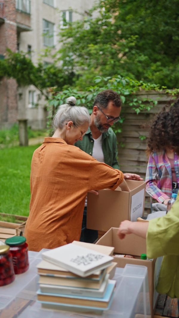 A collection drive. Volunteers collecting food resources and clothes to support people in need, working together.