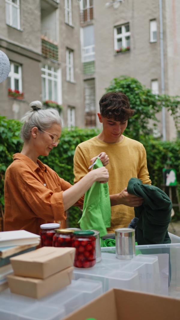 A collection drive. Volunteers collecting food resources and clothes to support people in need, working together.