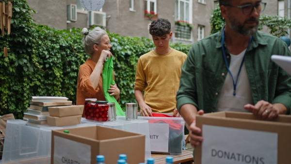 A collection drive. Volunteers collecting food resources and clothes to support people in need, working together.