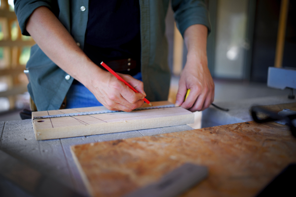 Carpenter measuring wooden planks and making marks with pencil. Carpentry concept.