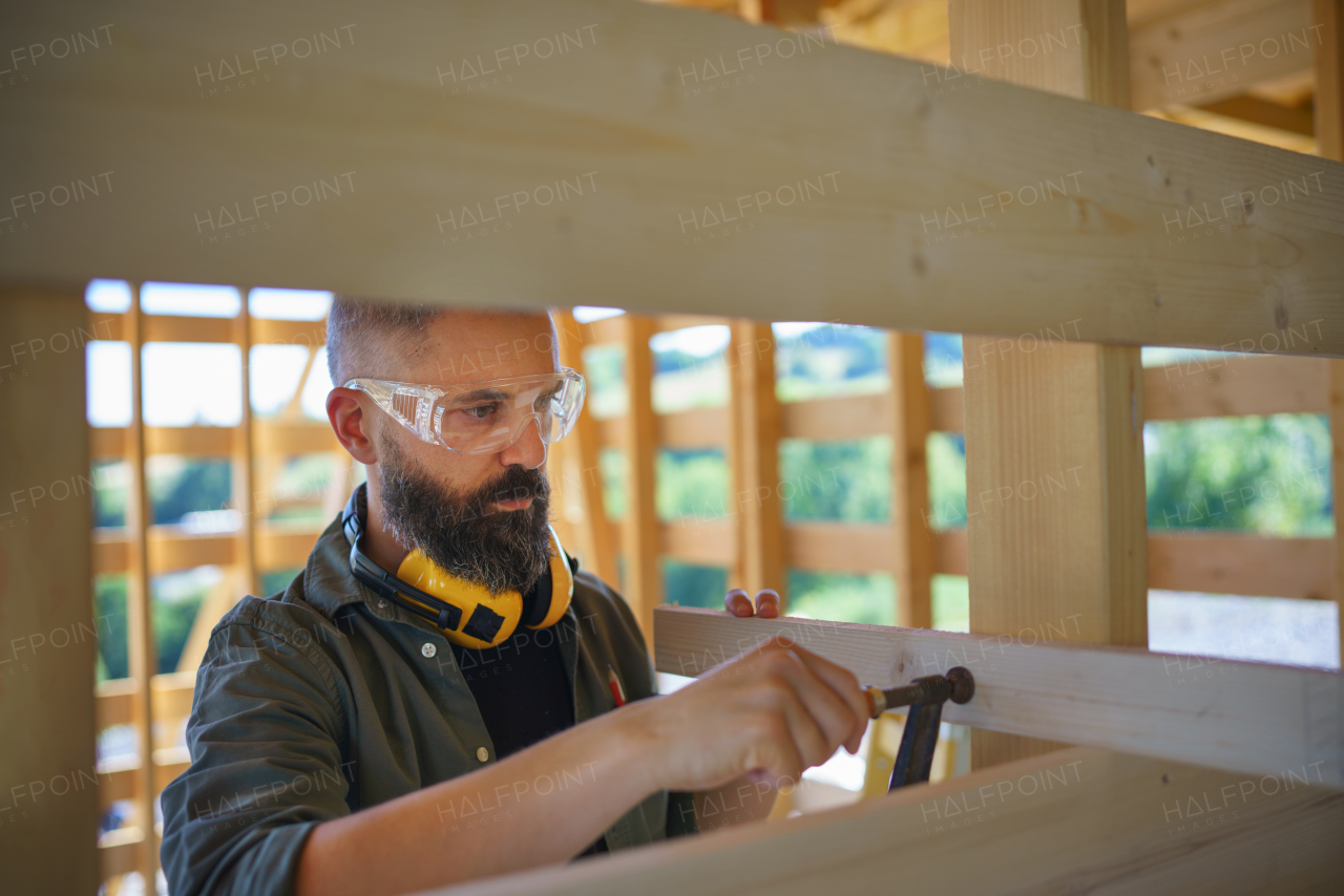 Construction worker manual working on a wooden frame, diy eco-friendly homes and sustainable lifestyle concept.