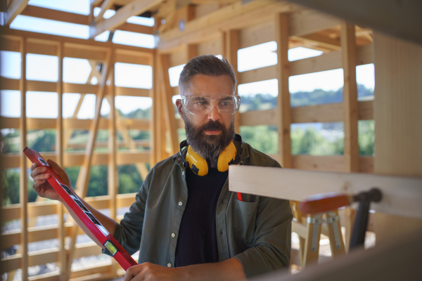 Carpenter checking a wooden planks with spirit level, diy eco-friendly homes concept.