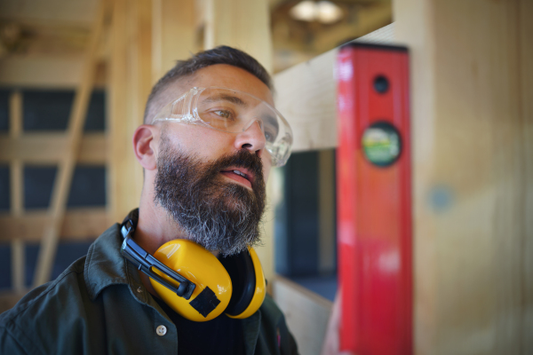 Carpenter checking a wooden planks with spirit level, diy eco-friendly homes concept.