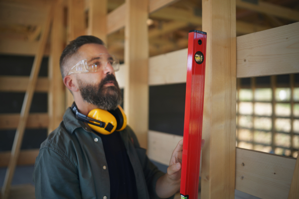 Carpenter checking a wooden planks with spirit level, diy eco-friendly homes concept.