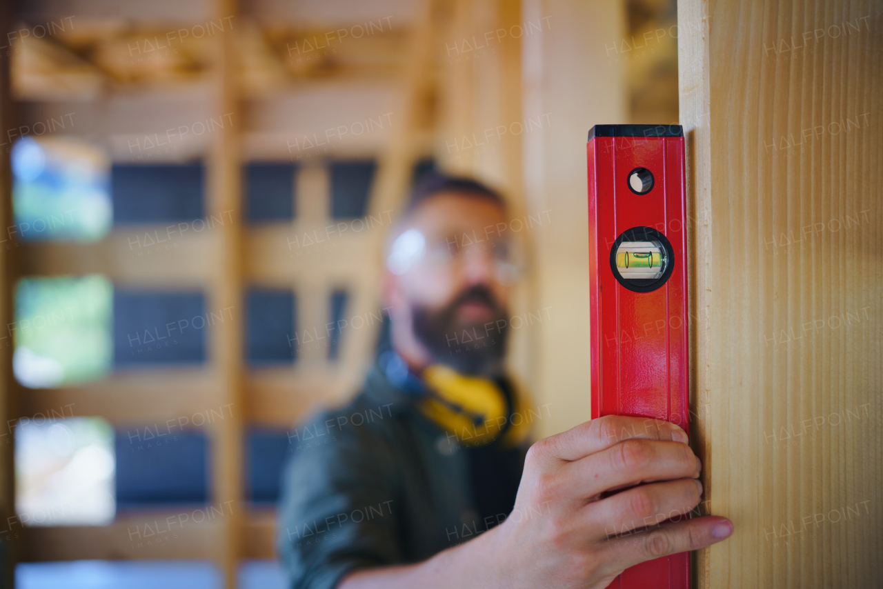 Carpenter checking a wooden planks with spirit level, diy eco-friendly homes concept.