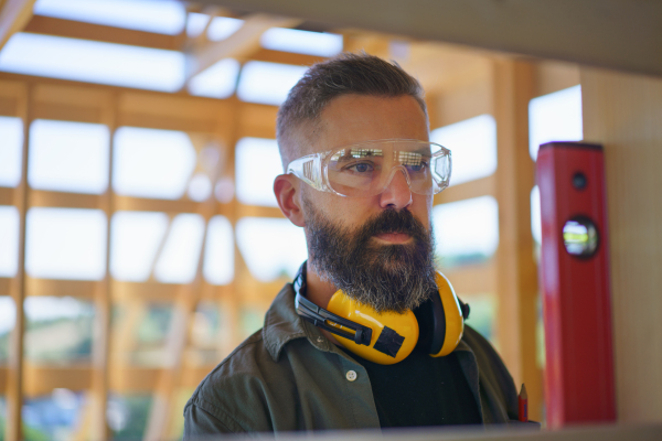 Carpenter checking a wooden planks with spirit level, diy eco-friendly homes concept.