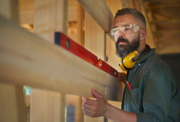 Carpenter checking a wooden planks with spirit level, diy eco-friendly homes concept.