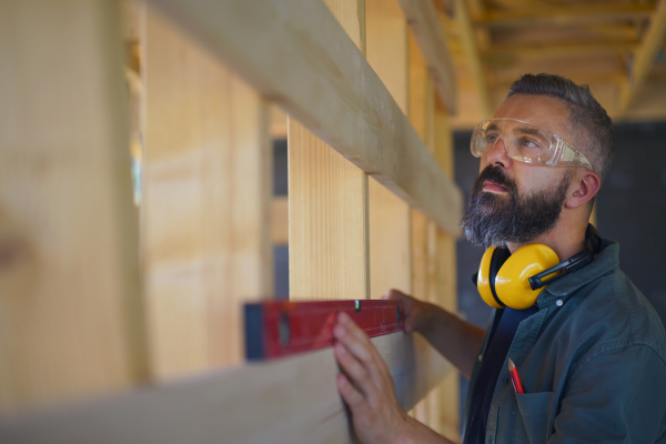 Carpenter checking a wooden planks with spirit level, diy eco-friendly homes concept.