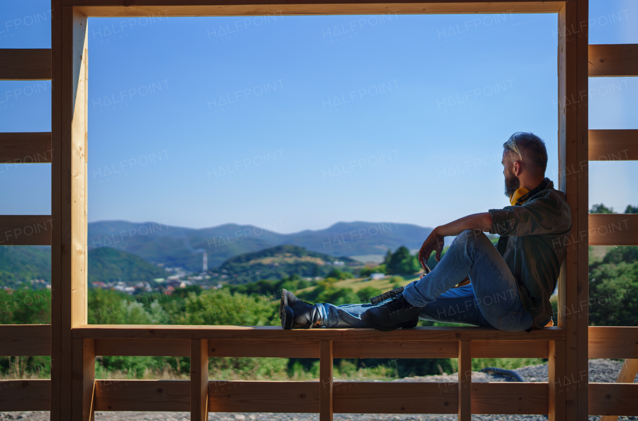 A handyman resting and having break when working on wooden construction site, diy eco-friendly homes concept.