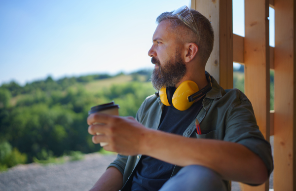 A handyman resting and having break when working on wooden construction site, diy eco-friendly homes concept.