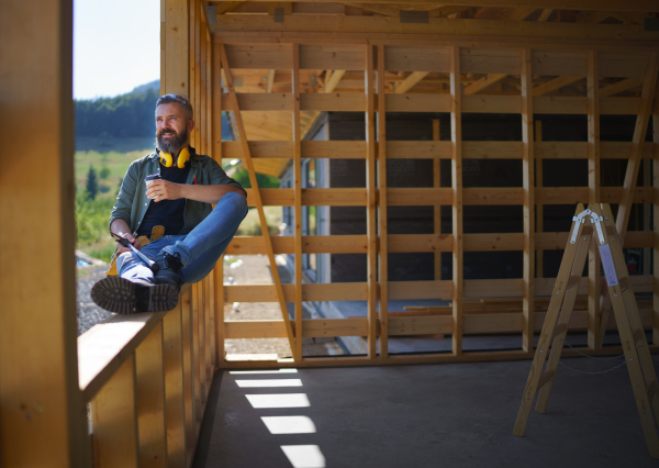 A handyman resting and having break when working on wooden construction site, diy eco-friendly homes concept.