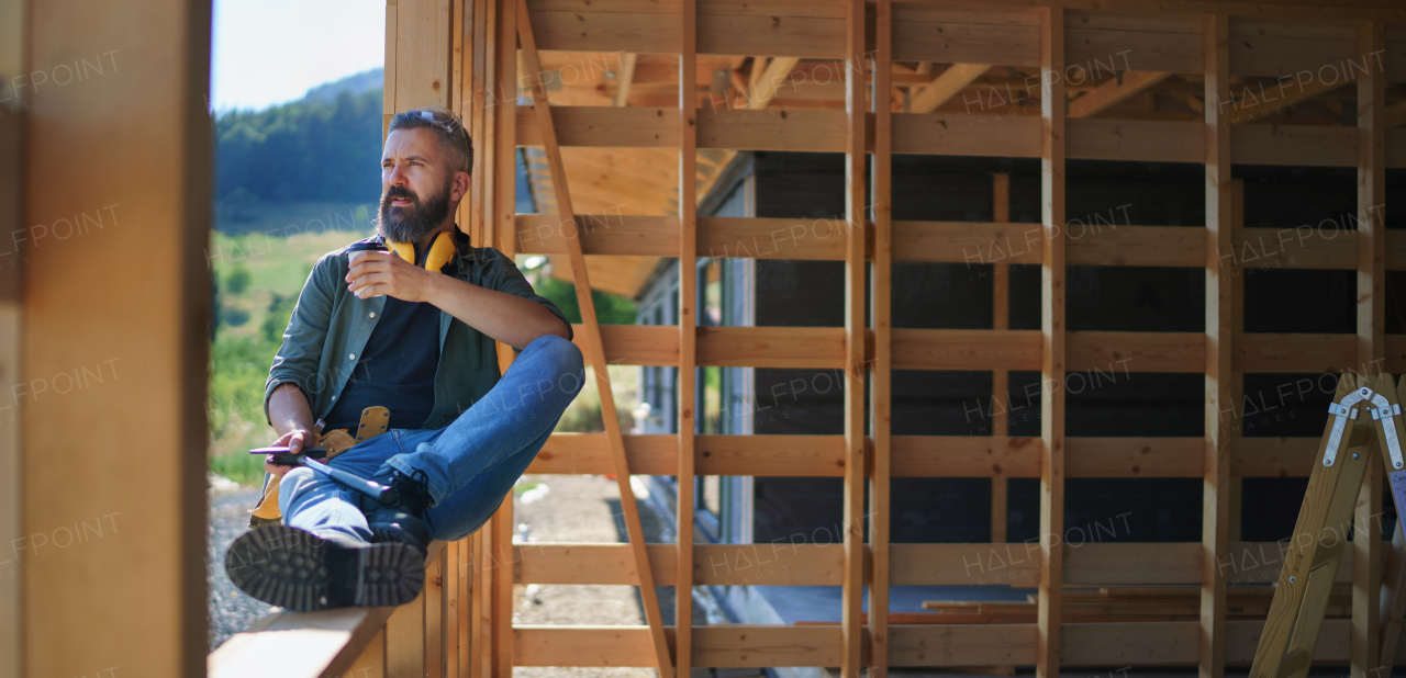 A handyman resting and having break when working on wooden construction site, diy eco-friendly homes concept.