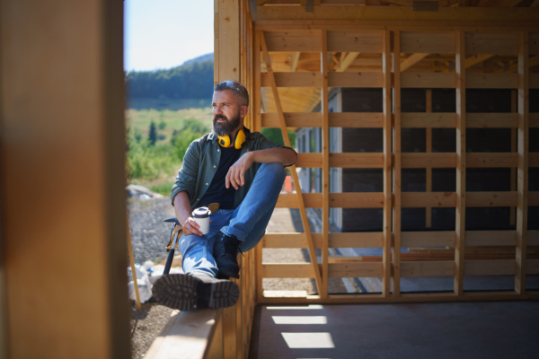 A handyman resting and having break when working on wooden construction site, diy eco-friendly homes concept.