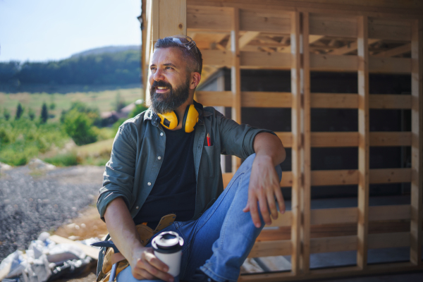 A handyman resting and having break when working on wooden construction site, diy eco-friendly homes concept.