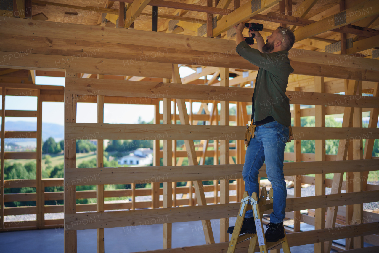 A construction worker working with screwdriver on wooden frame, diy eco-friendly homes concept.