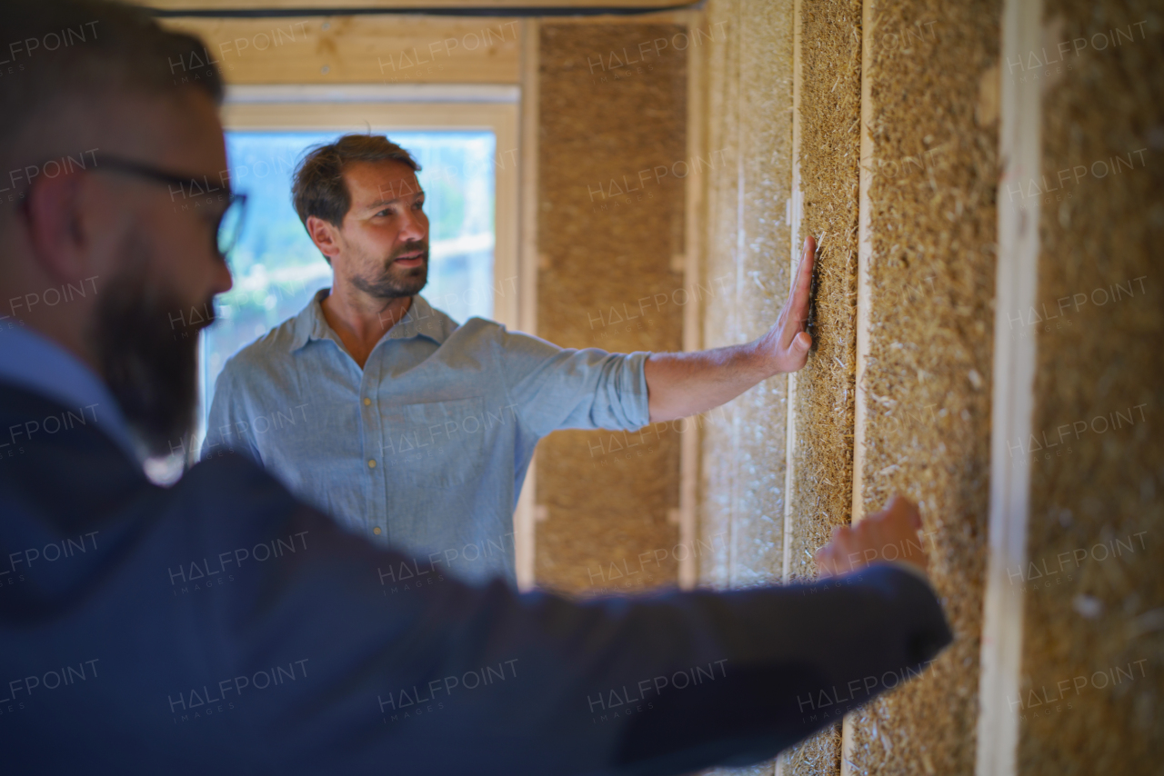 Developer showing an unfinished wooden house customer, diy eco-friendly homes concept.