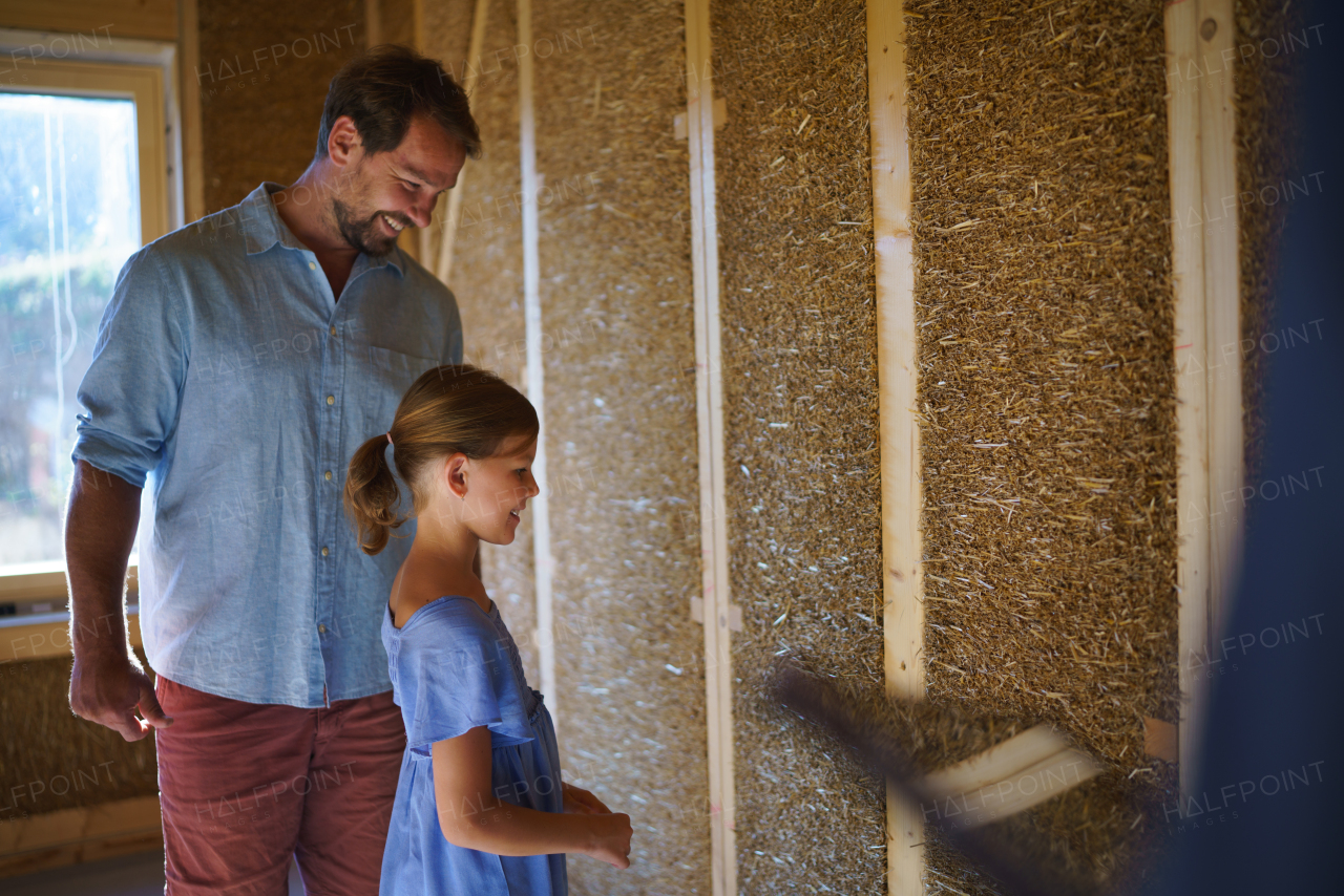 Father with his little daughter checking their unfinished wooden house, diy eco-friendly home concept.