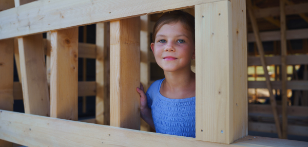 Portrait of a little girl in wooden construction of their unfinished wooden eco house.