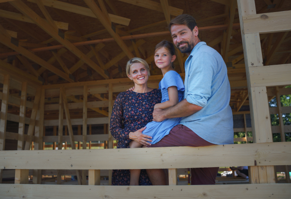 Young family on site inside of new ecology wooden home construction framing.