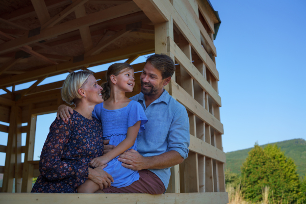 A young family on site inside new home construction framing.