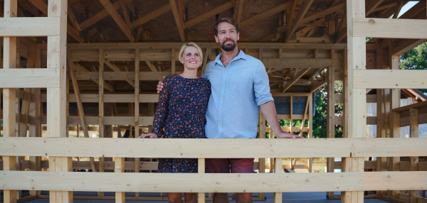 A young couple on site inside construction framing dreaming of her new home.