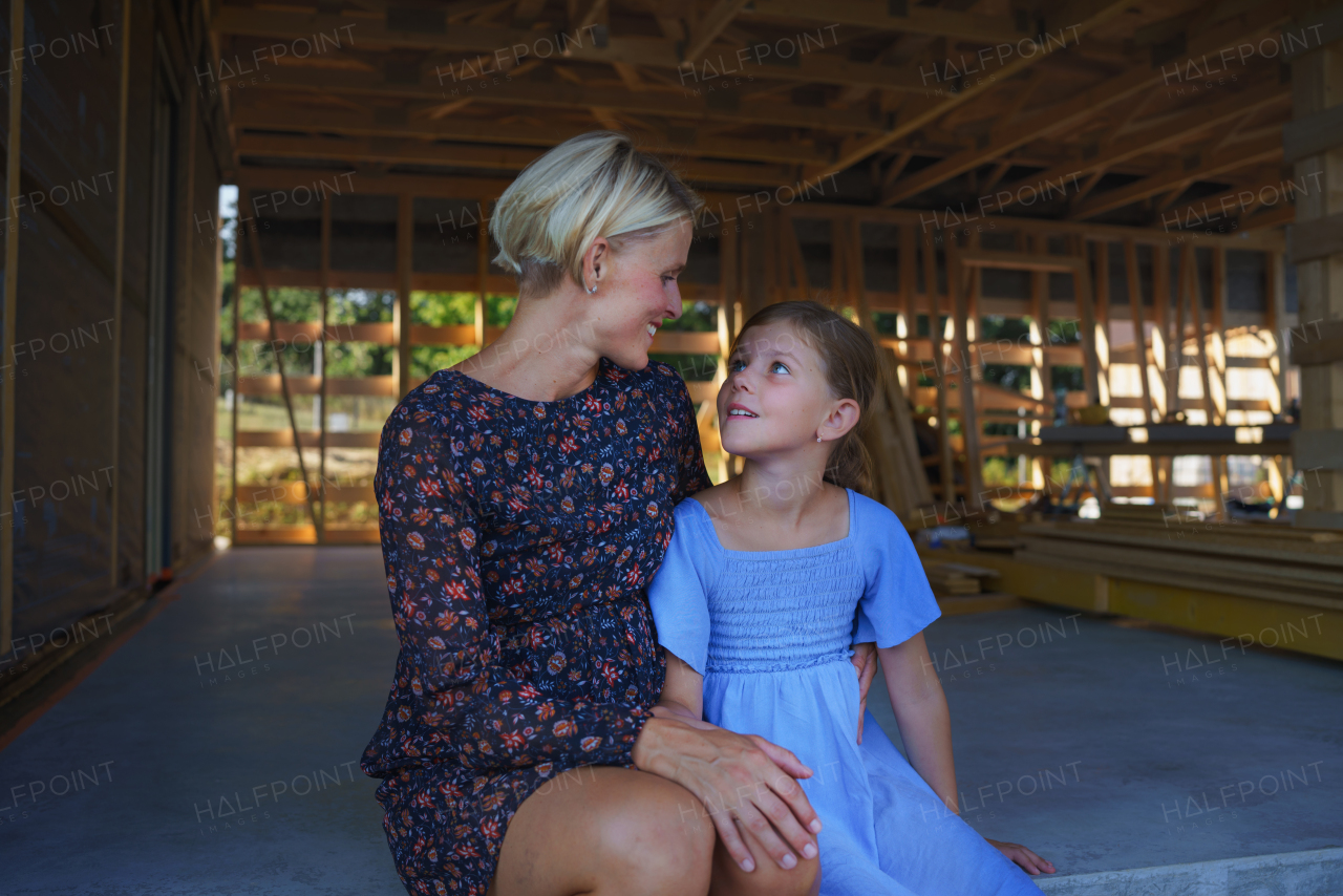 Mother and daughter inside their new unfinished ecology wooden house.