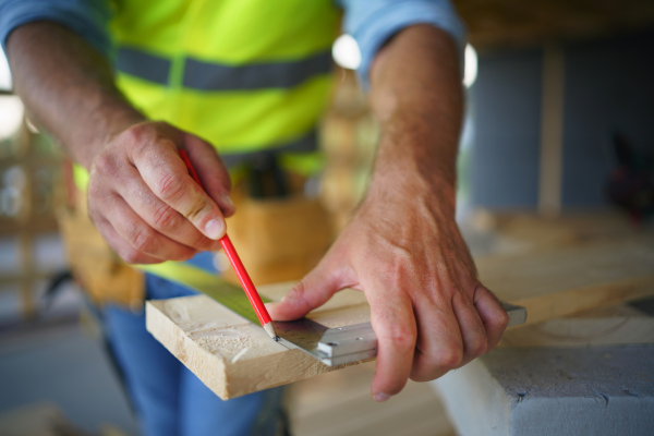 Carpenter measuring wooden planks and making marks with pencil. Carpentry concept.