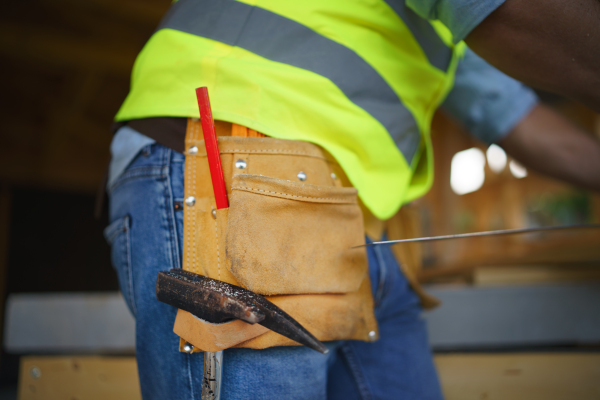 Close-up of unrecognizable construction worker in protective clothes and his working tools.