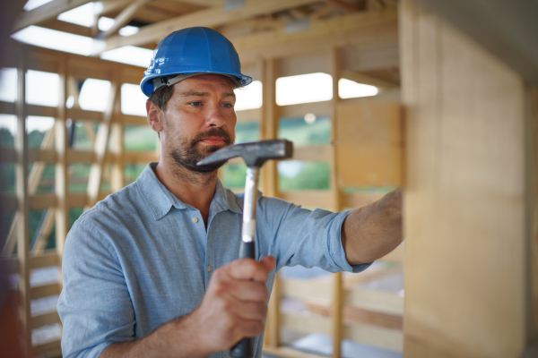 A construction worker working with screwdriver on wooden frame, diy eco-friendly homes concept.