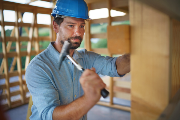 A construction worker working with screwdriver on wooden frame, diy eco-friendly homes concept.