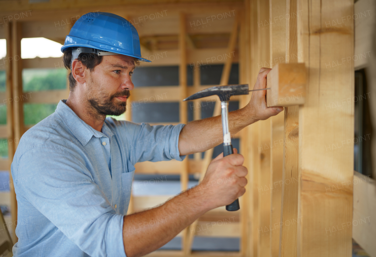 A construction worker working with screwdriver on wooden frame, diy eco-friendly homes concept.