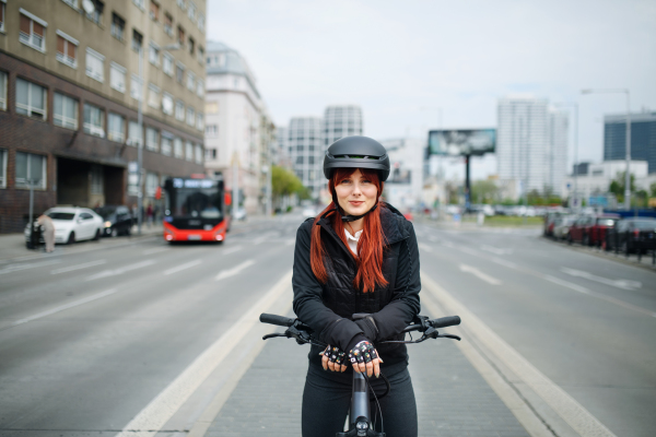 A portrait of businesswoman commuter on the way to work with bike looking at camera, sustainable lifestyle concept.