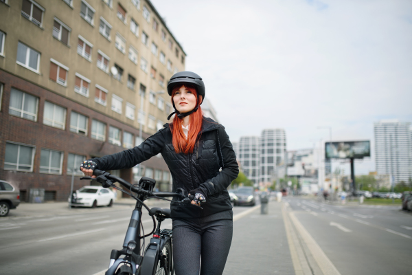 A portrait of businesswoman commuter on the way to work with bike looking at camera, sustainable lifestyle concept.