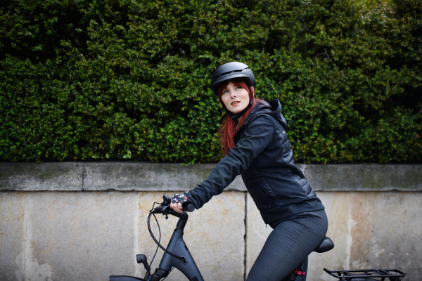 A portrait of businesswoman commuter on the way to work with bike looking at camera, sustainable lifestyle concept.