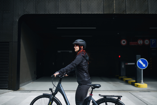 A portrait of businesswoman commuter on the way to work with bike looking at camera, sustainable lifestyle concept.