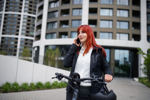 A portrait of businesswoman commuter on the way to work with bike, sustainable lifestyle concept.