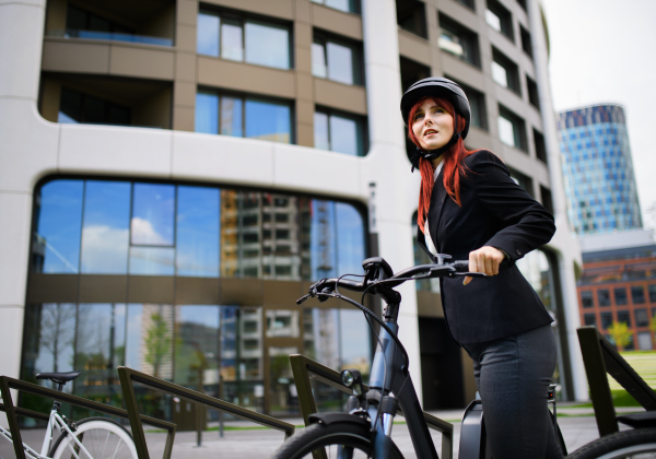 A portrait of businesswoman commuter on the way to work with bike looking at camera, sustainable lifestyle concept.