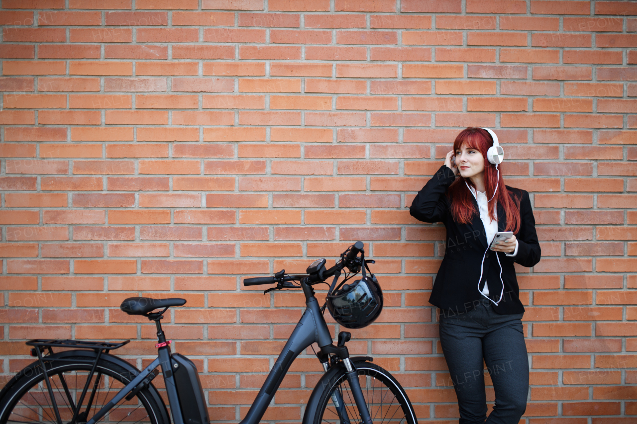 A portrait of businesswoman commuter on the way to work with bike, resting listening to music, sustainable lifestyle concept.