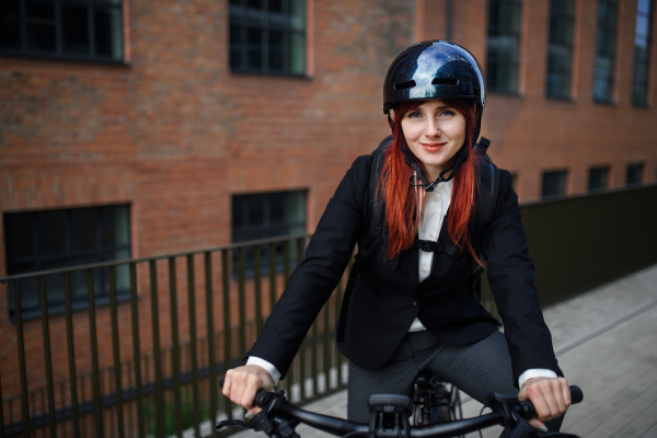 A portrait of businesswoman commuter on the way to work with bike, sustainable lifestyle concept.