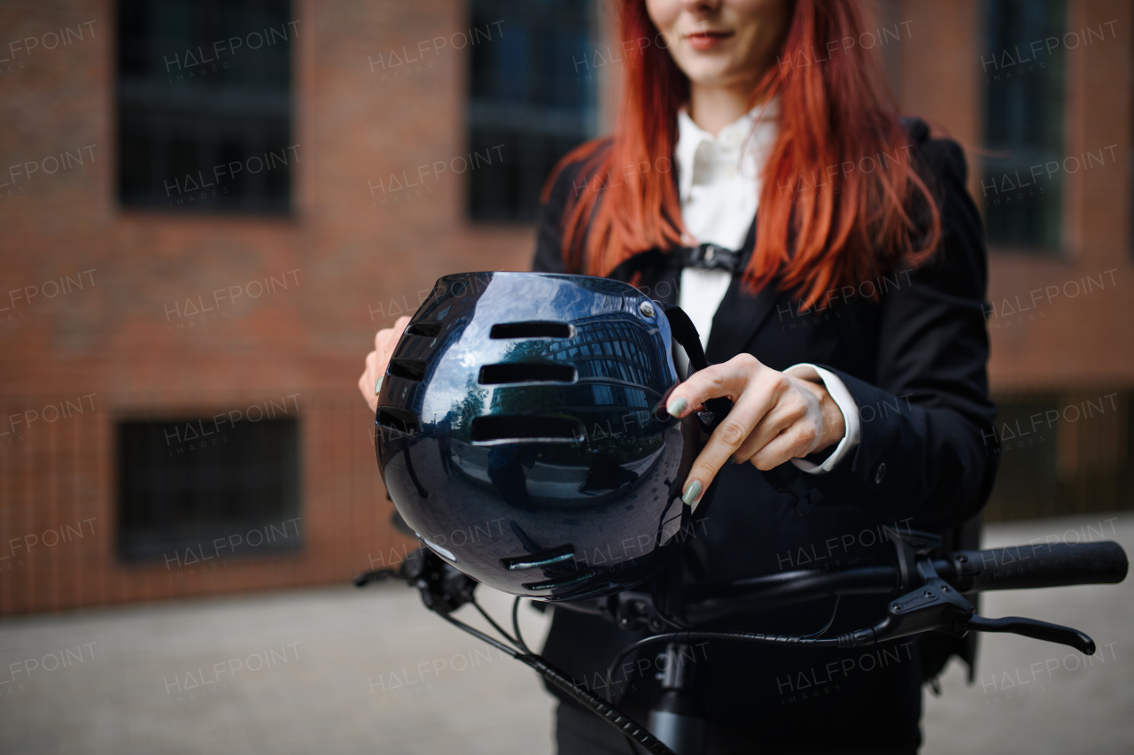 Close-up of businesswoman commuter on way to work putting on cycling helmet, sustainable lifestyle concept.